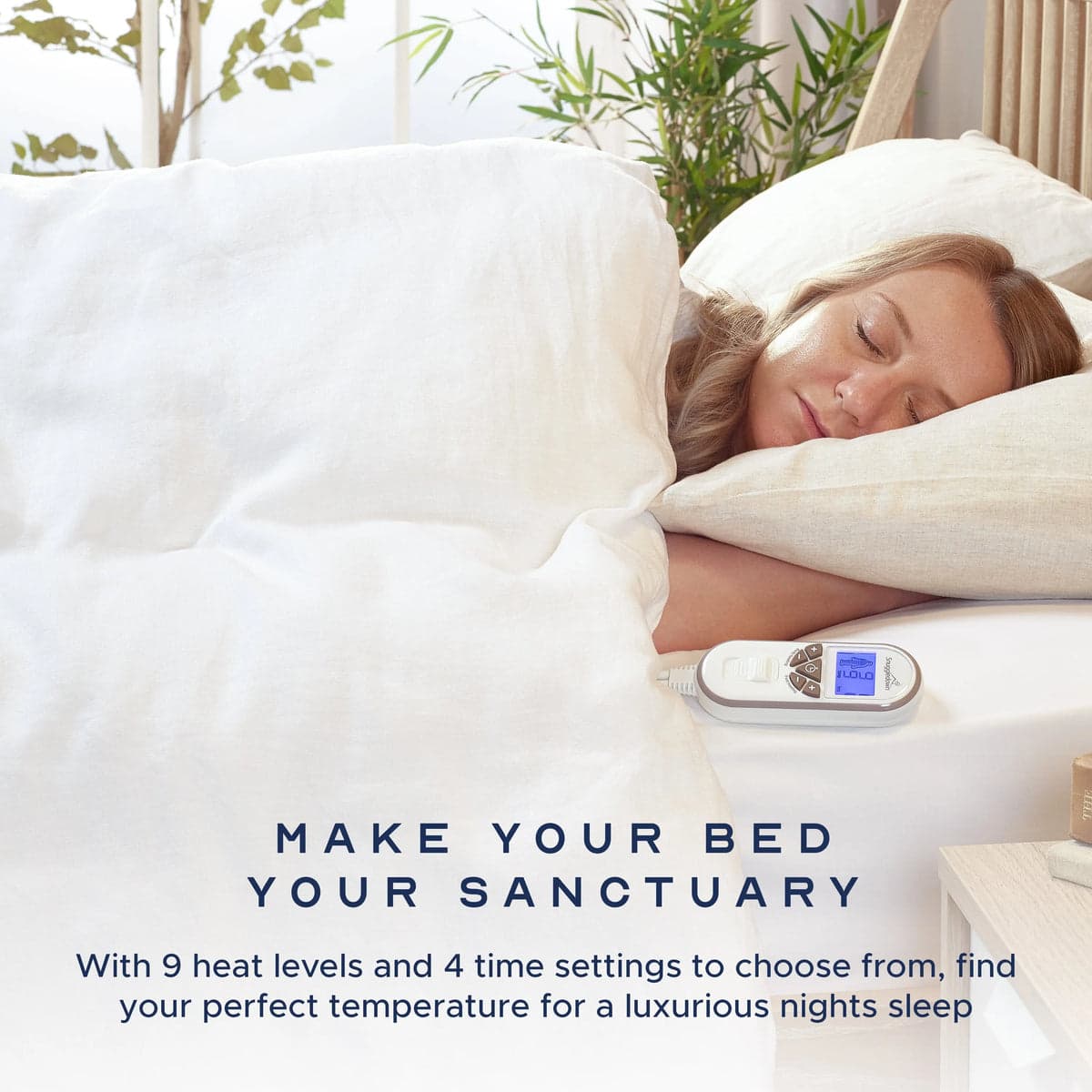 A woman asleep under white bedding with the heated underblanket controller resting on the mattress beside her.